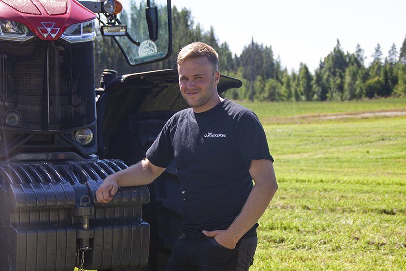 Kesätyöntekijä Matias seisomassa pellolla Massey Ferguson -traktorin edessä