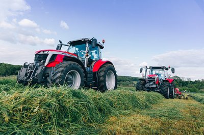 Kaksi Massey Ferguson traktoria traktoria pellolla rehunteossa.