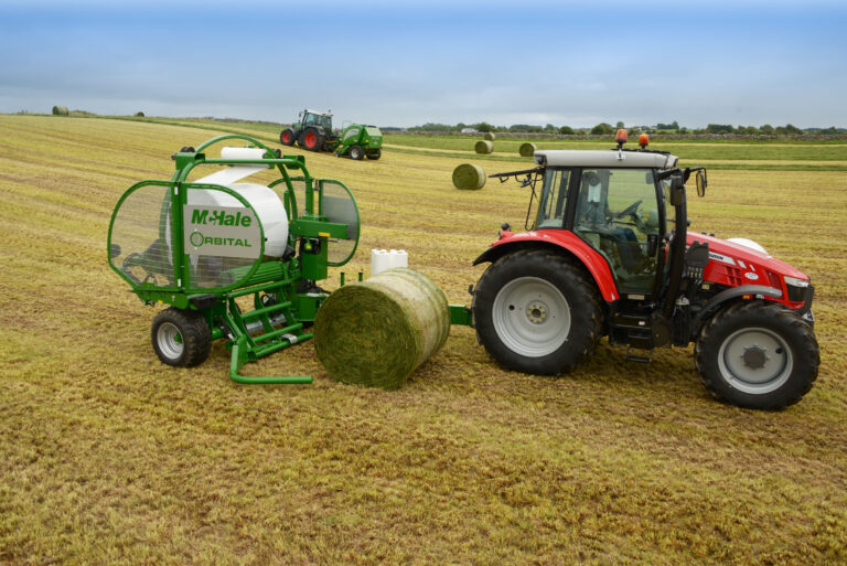 McHale Orbital käärin käärii pyöröpaalia. Kuvassa myös Massey Ferguson traktori.