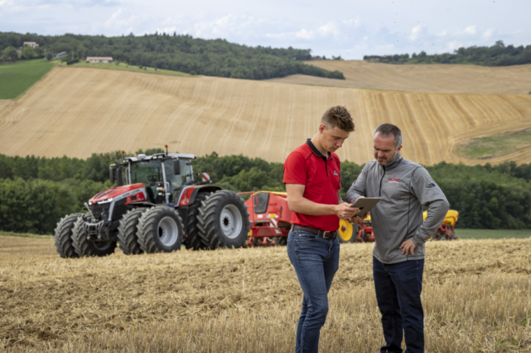 Massey Ferguson -traktori pellolla kahden henkilön kanssa, jossa he tutustuvat uuteen AGCO Parts -varaosien verkkokauppaan.