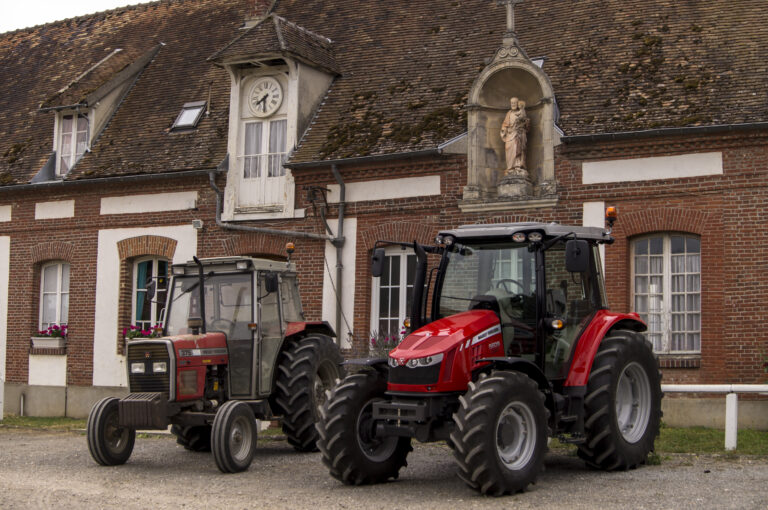 Kaksi Massey Ferguson -traktoria vanhan rakennuksen edessä.