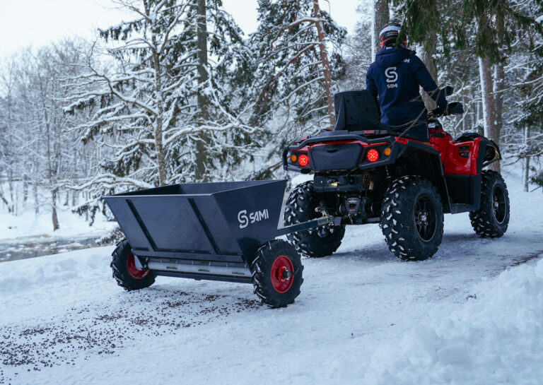 Sami S-290 hiekoitin mönkijän perässä ja hiekoitus käynnissä.
