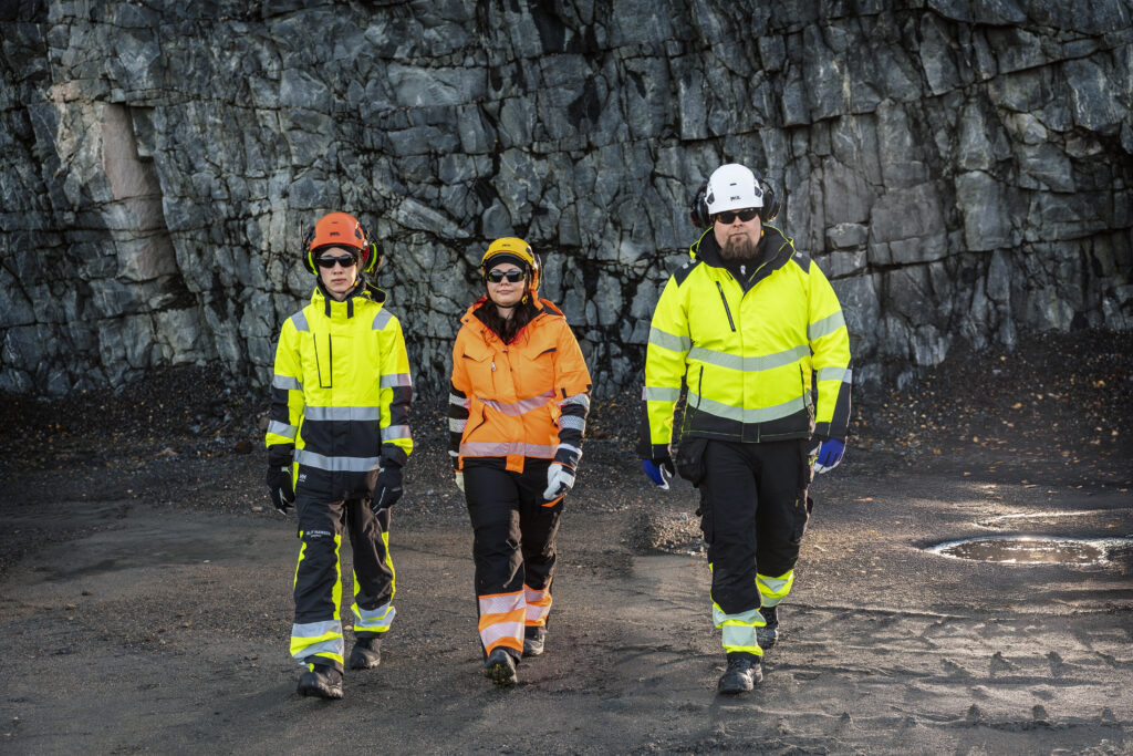 3 ihmistä kävelemässä ulkona Helly Hansen, Patron ja Blåkläder -työvaatteet päällä.