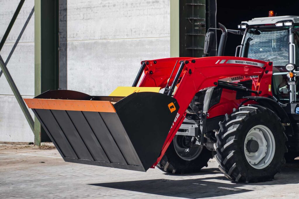 Massey Ferguson traktori etukuormaajalla ajaa ulos varastorakennuksesta.