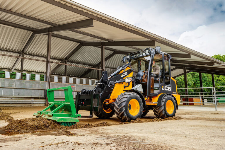 JCB 403 Agri -pyöräkuormaaja lakaisemassa navetan lattiaa.