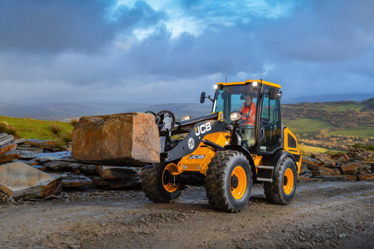 JCB 409 Agri -pyöräkuormaaja siirtämässä kiveä työmaalla.