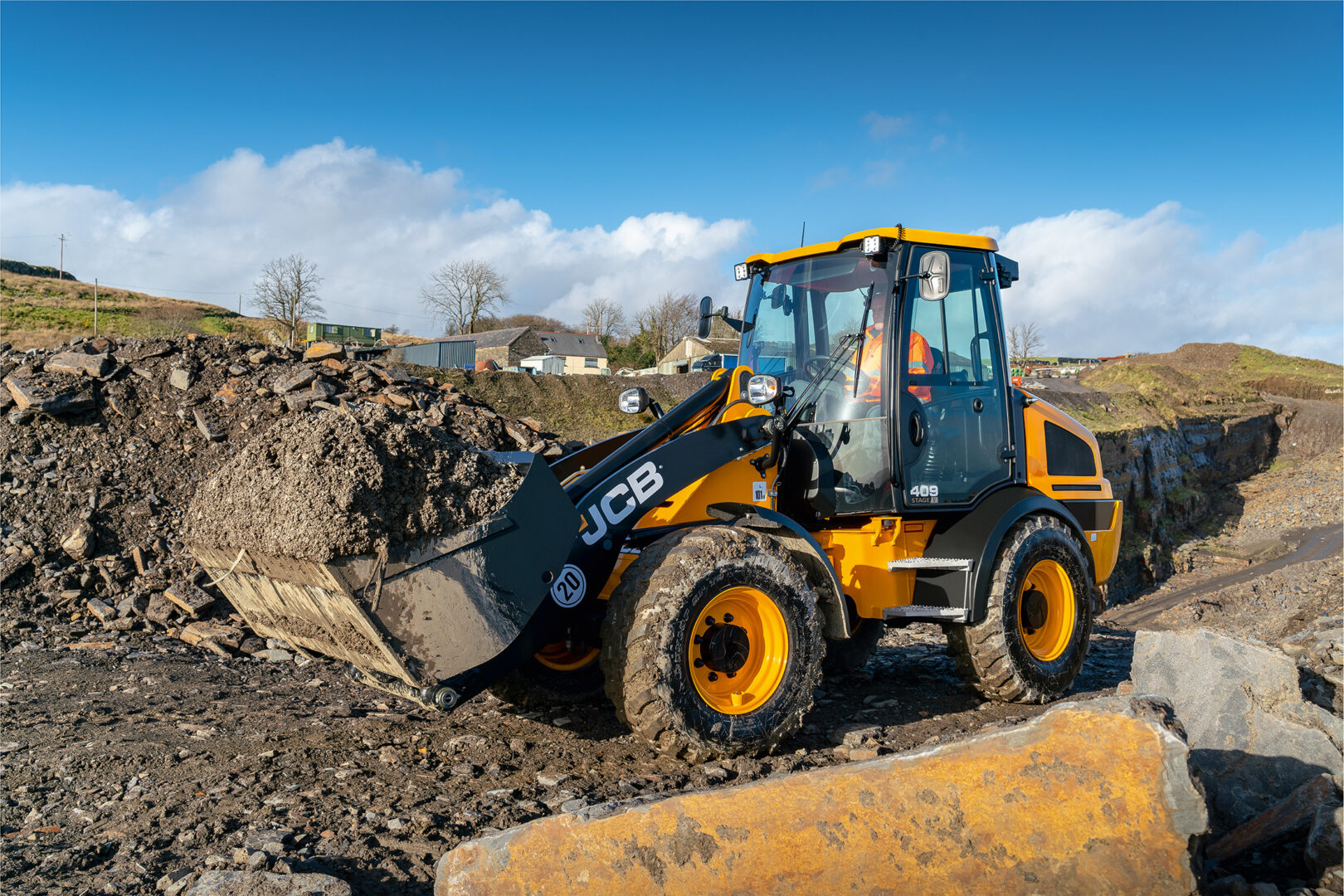 JCB 409 Agri -pyöräkuormaaja siirtämässä maata työmaalla.