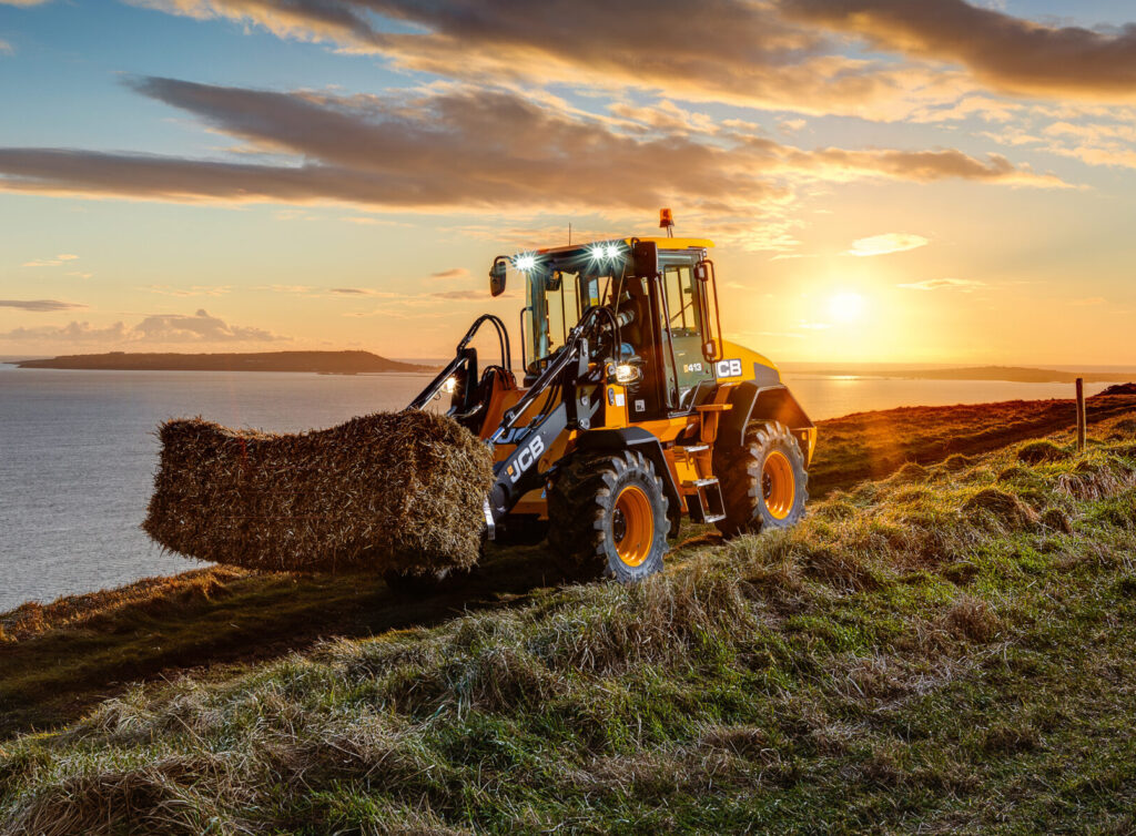 JCB 413S-pyöräkuormaaja siirtämässä heinää maatilalla.