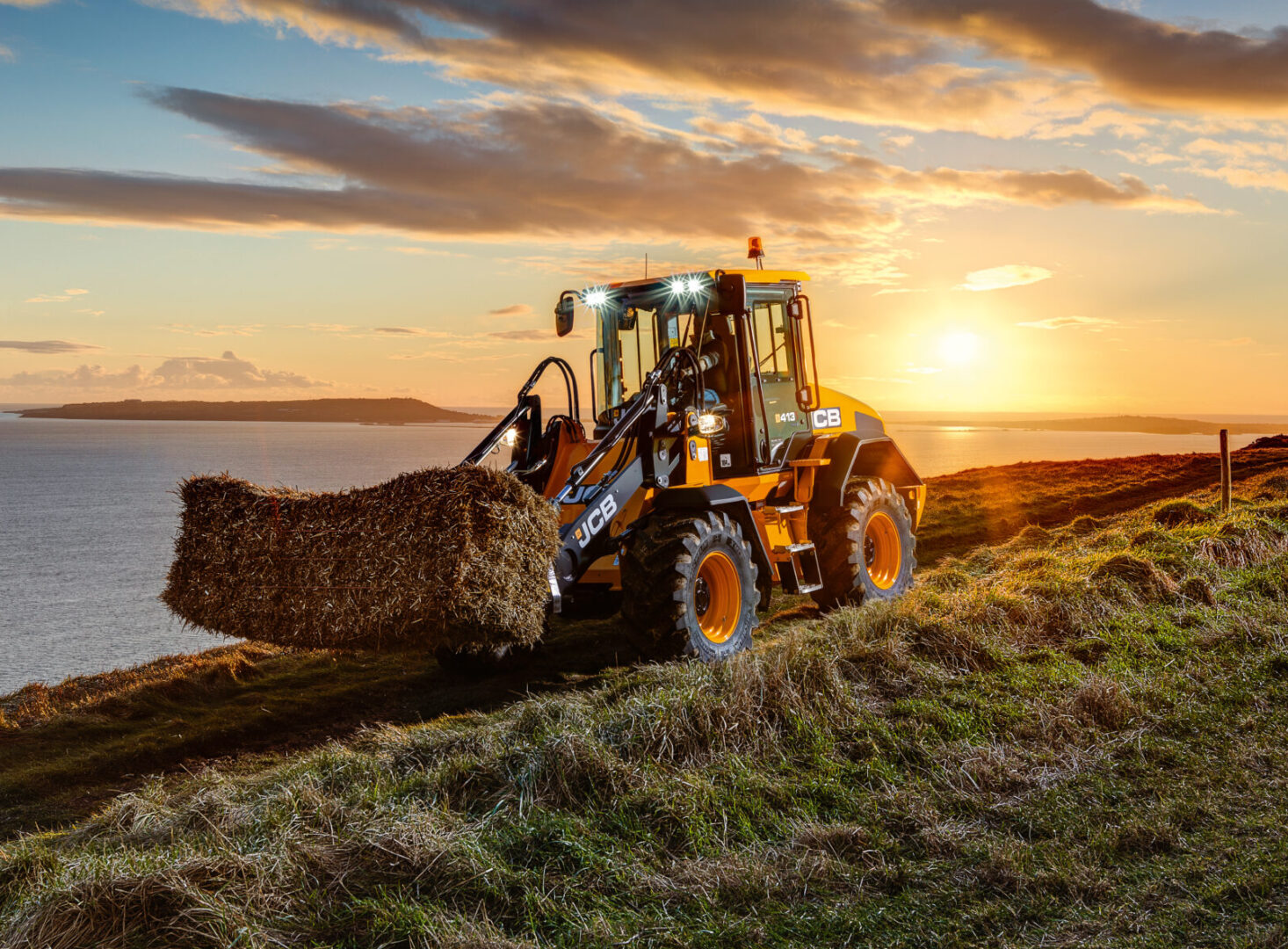 JCB 413S-pyöräkuormaaja siirtämässä heinää maatilalla.