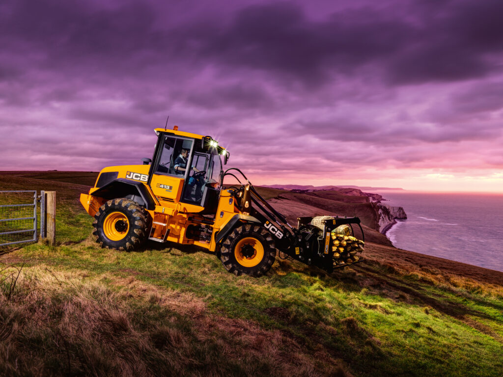 JCB 413S-pyöräkuormaaja siirtämässä heinäseipäitä.
