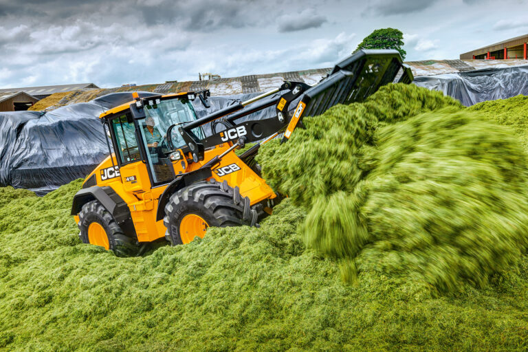 JCB 419S-pyöräkuormaaja työntämällä rehua aumalla.