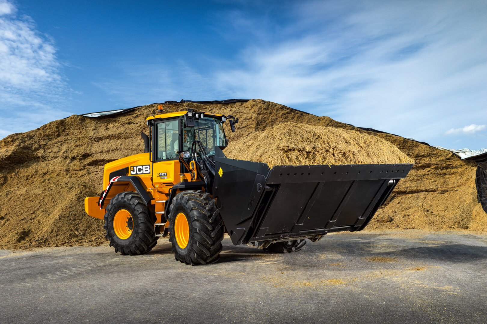JCB 427 Agri-pyöräkuormaaja nostamassa rehua.