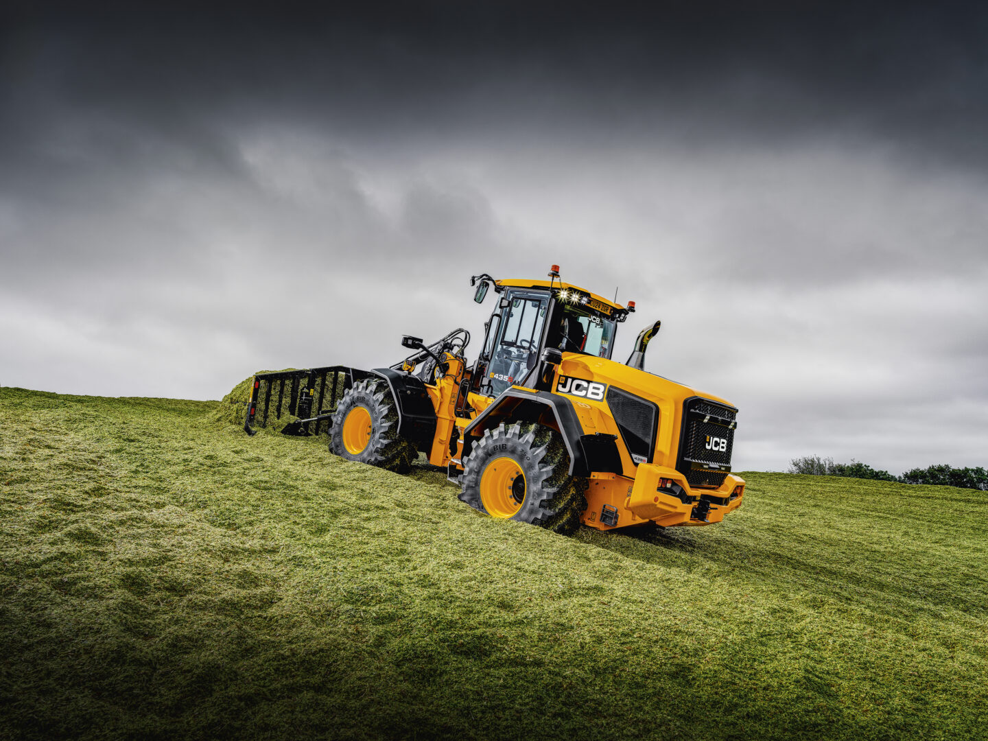 JCB 435S -pyöräkuormaaja aumalla työntämässä rehua.