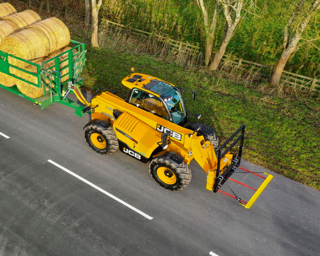 JCB 542-70 Agrisuper -kurottaja tulossa pellolta heinäpaalien kanssa.