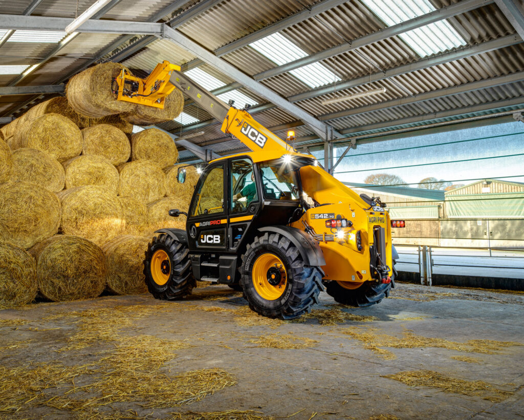 JCB 542-70 Agrisuper -kurottaja nostamassa olkipaaleja kasasta pois.