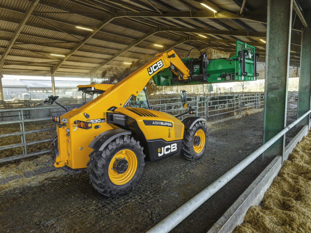 JCB 530-60 Agrisuper -kurottaja kuivittamassa navettaa oljella.