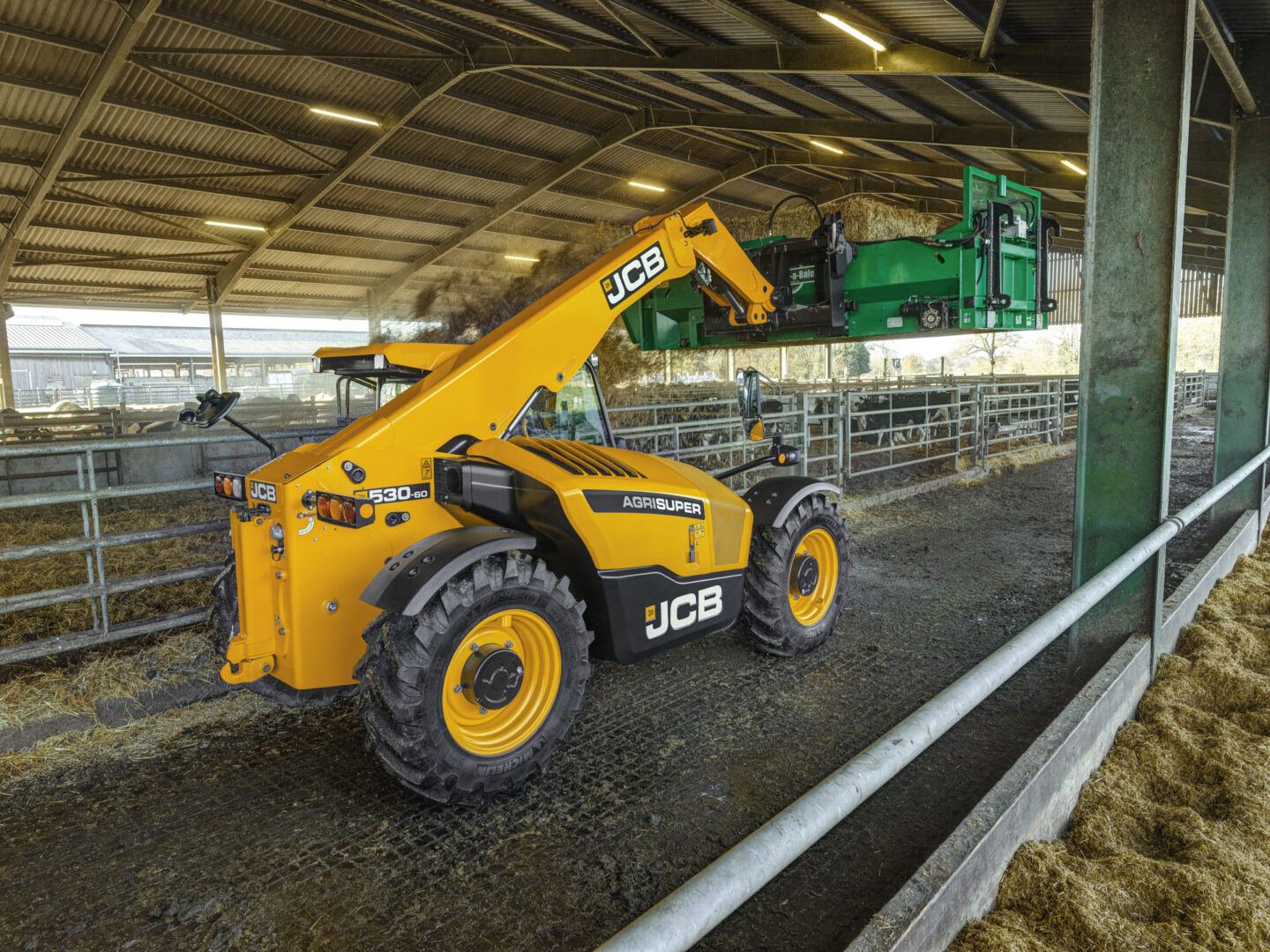 JCB 530-60 Agrisuper -kurottaja kuivittamassa navettaa oljella.