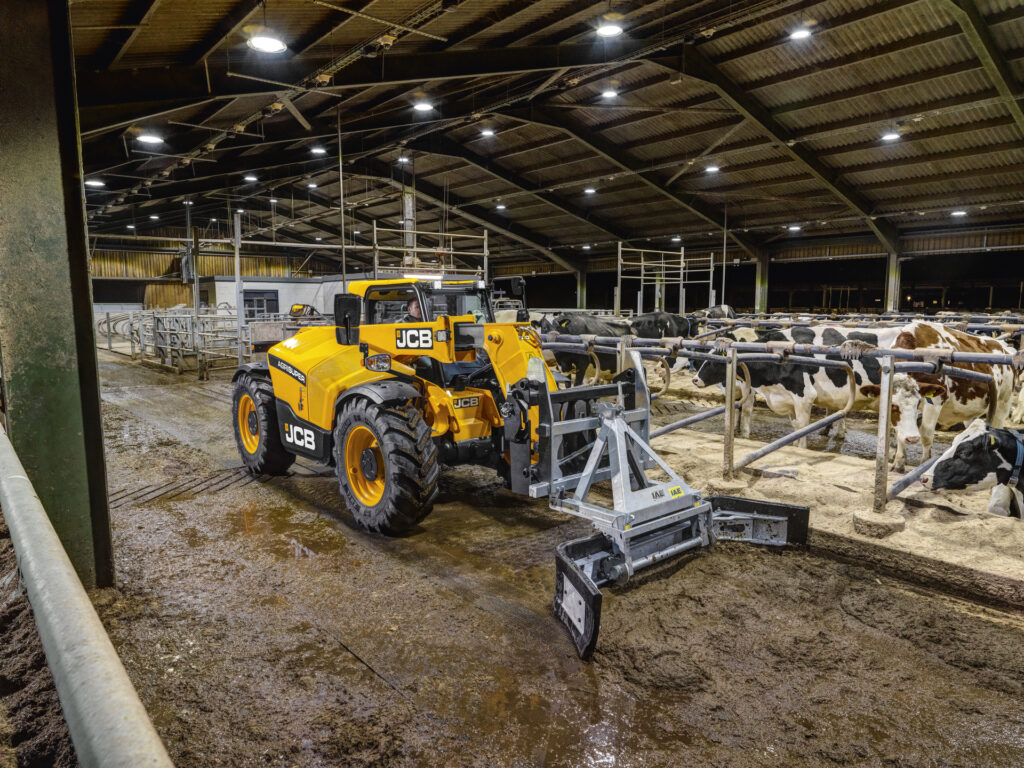 JCB 530-60 Agrisuper -kurottaja navetassa työntämässä lantaa.