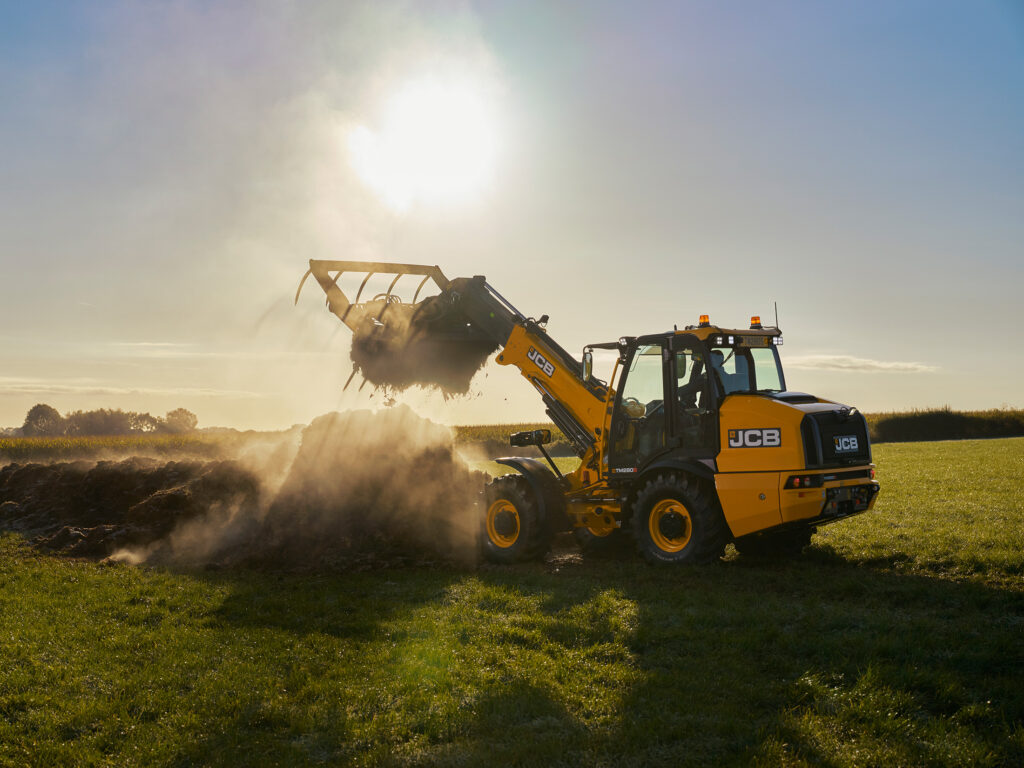 JCB TM280S Agri -kurottava pyöräkuormaaja pellolla tuomassa kuormaa.