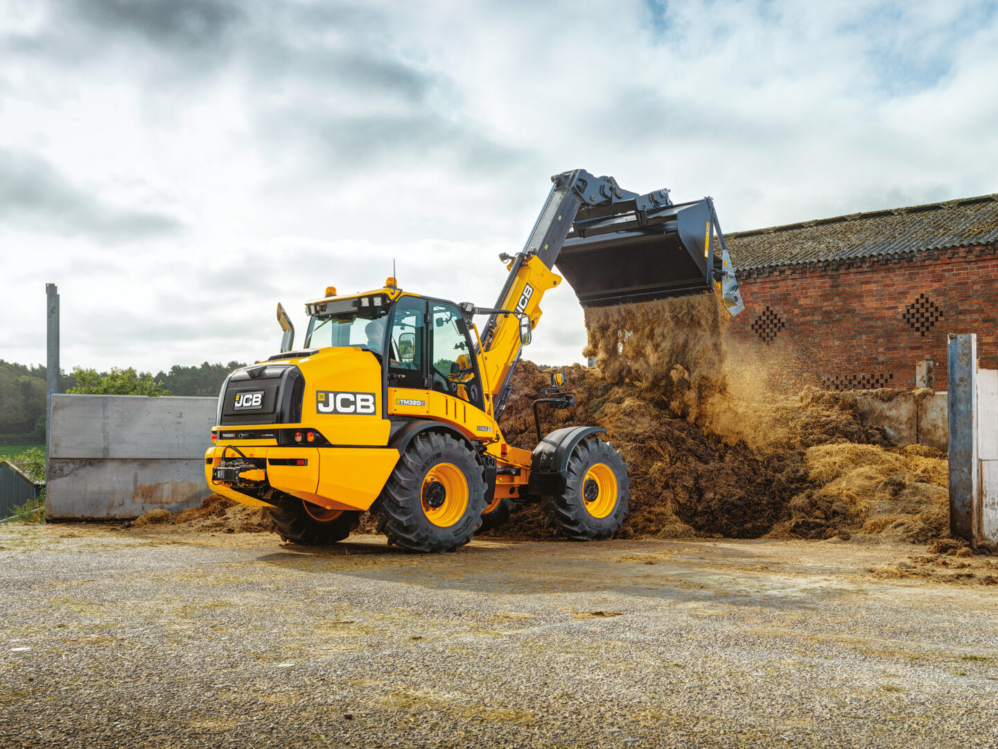 JCB TM320S Agri -kurottava pyöräkuormaaja kippaamassa lantaa.
