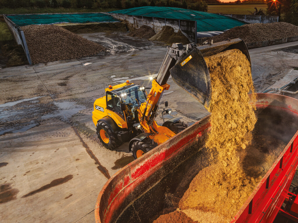 JCB TM420S Agri -kurottava pyöräkuormaaja kippaamassa rehua apevaunuun.