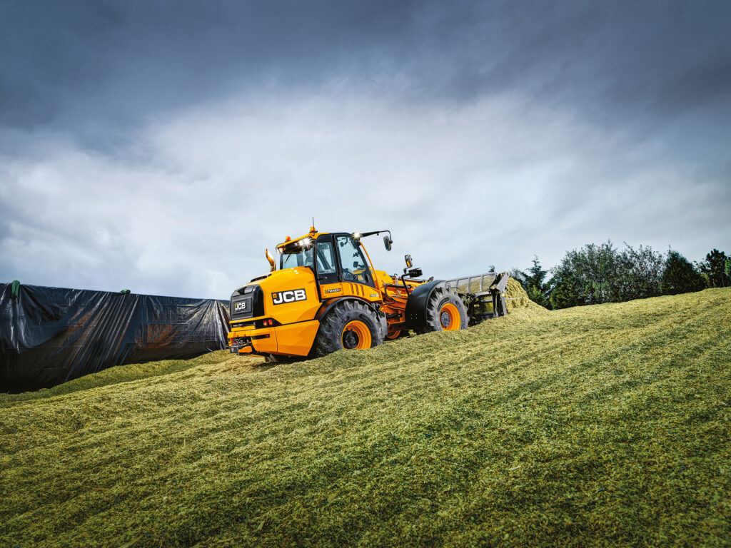JCB TM420S Agri -kurottava pyöräkuormaaja työntämässä rehua rehuaumalla.