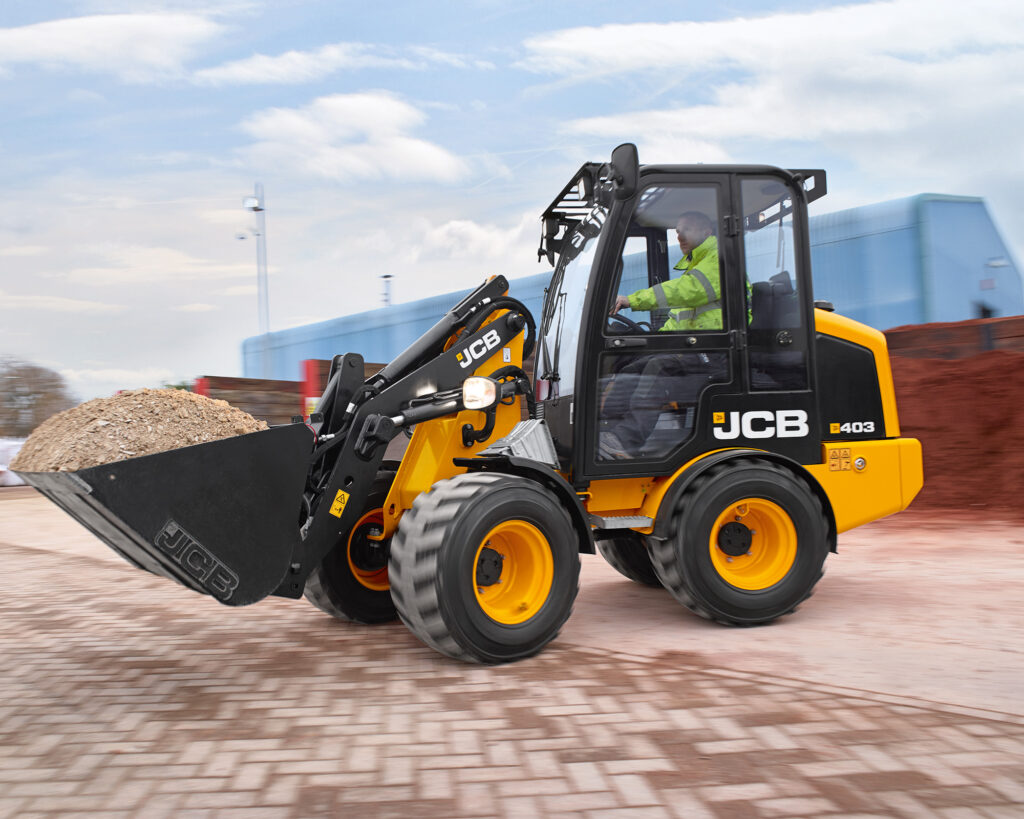 JCB 403 Agri -pyöräkuormaaja kantamassa maata työmaalla.