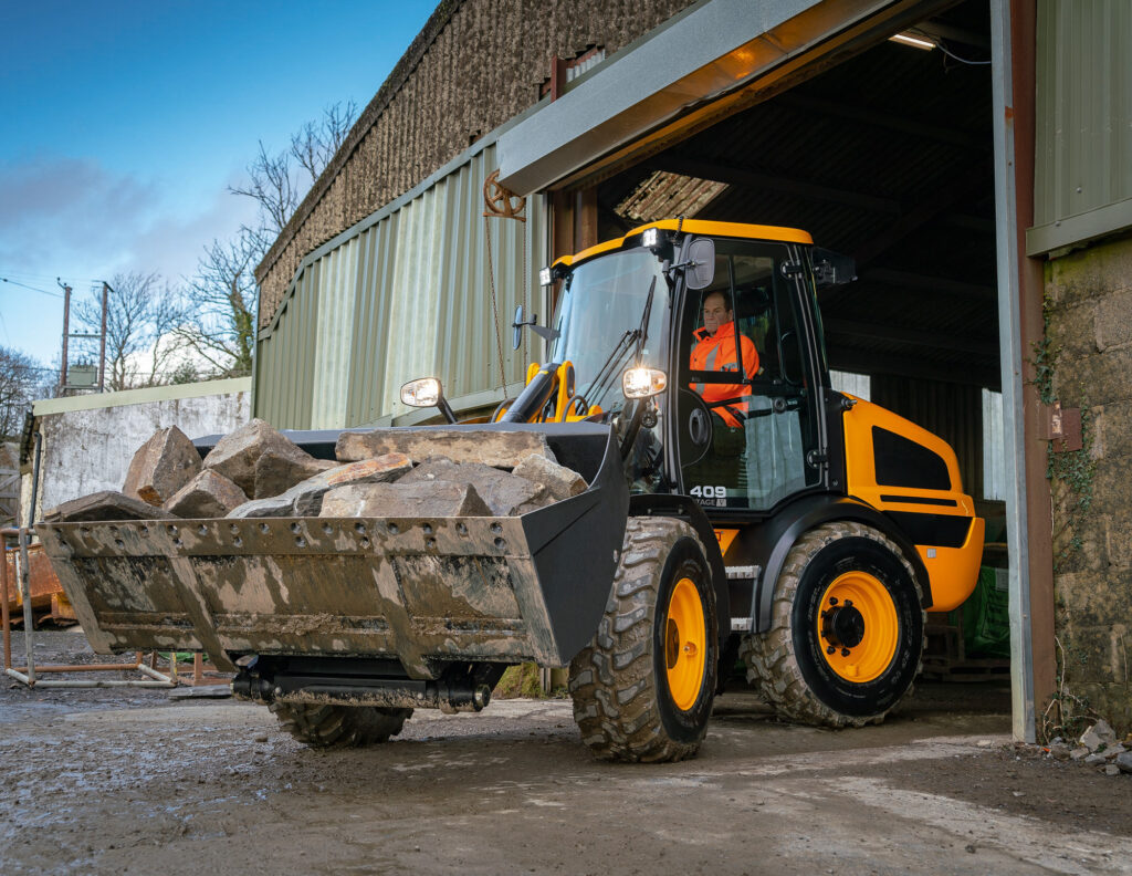 JCB 409 Agri -pyöräkuormaaja siirtämässä kiviä kauhassa.