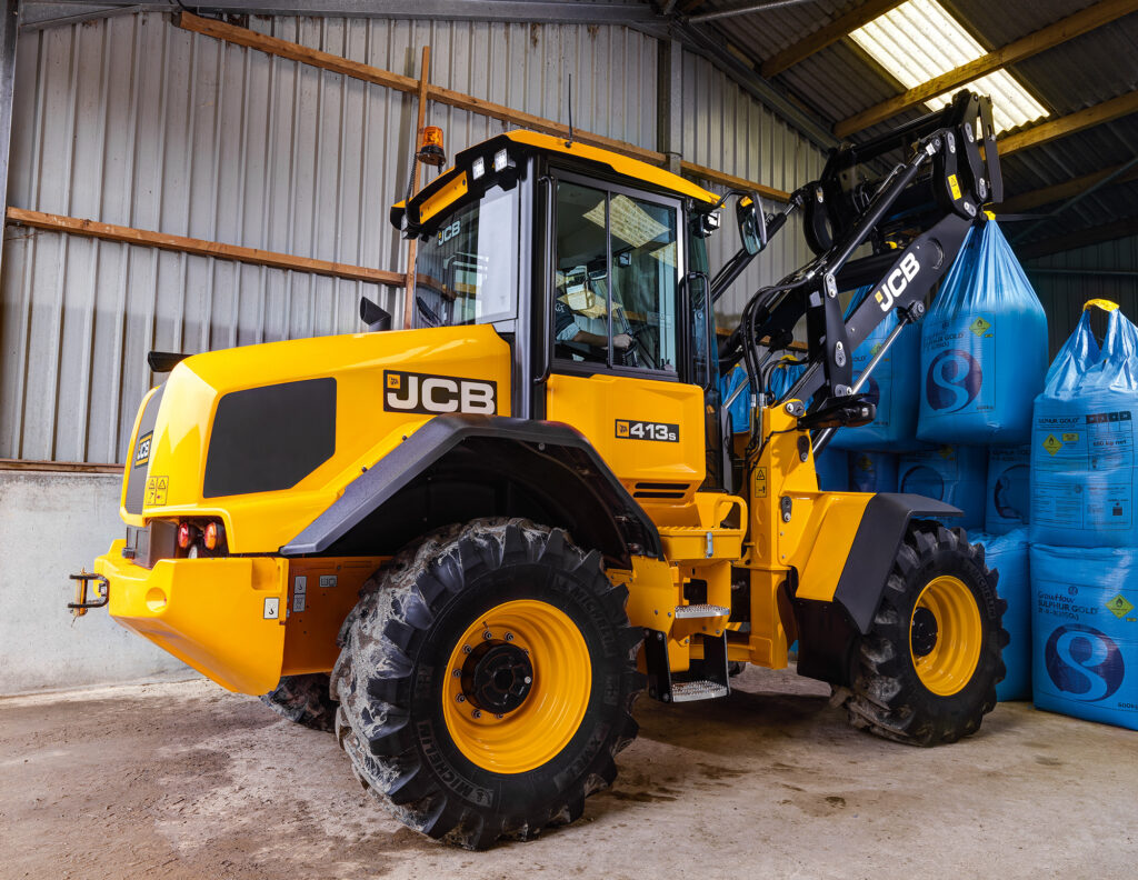 JCB 413S-pyöräkuormaaja nostamassa lannoitesäkkejä.