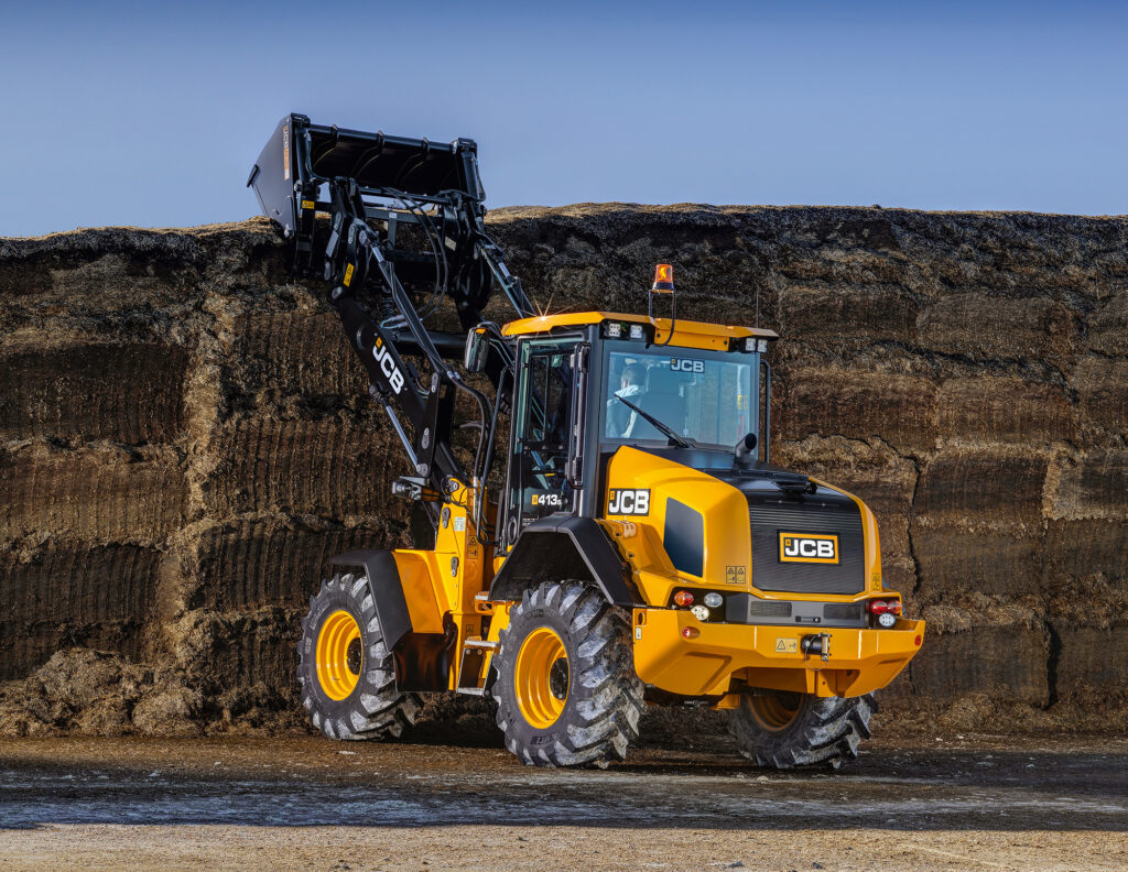 JCB 413S-pyöräkuormaaja nostamassa rehua aumasta.