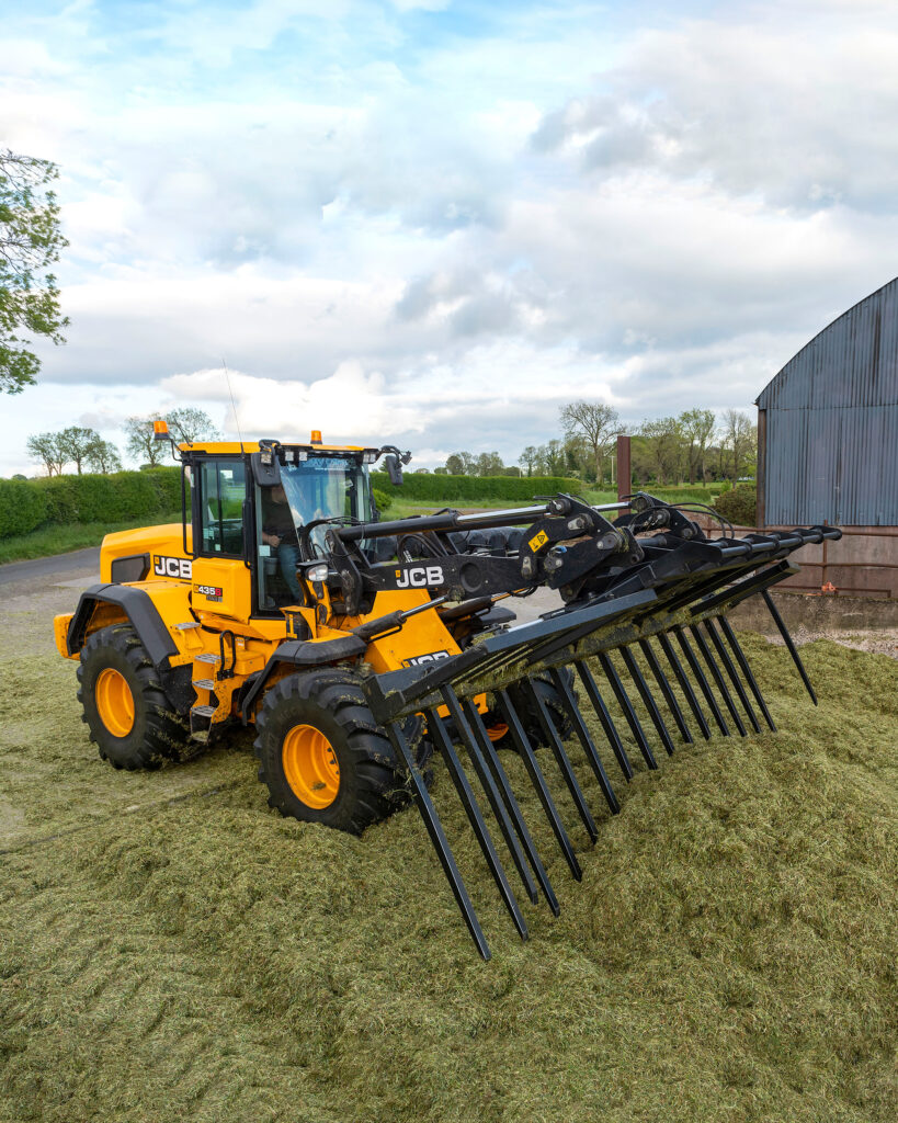 JCB 435S -pyöräkuormaaja aumalla työntämässä rehua.