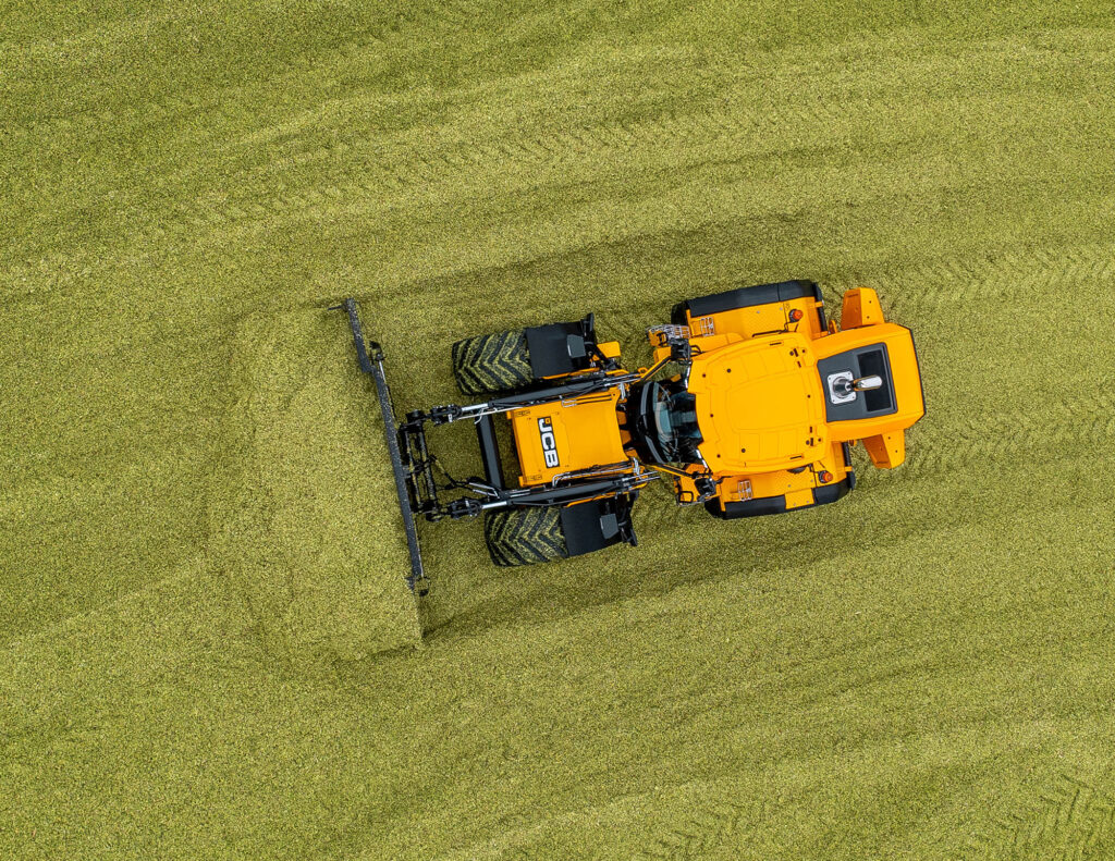 JCB 435S -pyöräkuormaaja aumalla työntämässä rehua.
