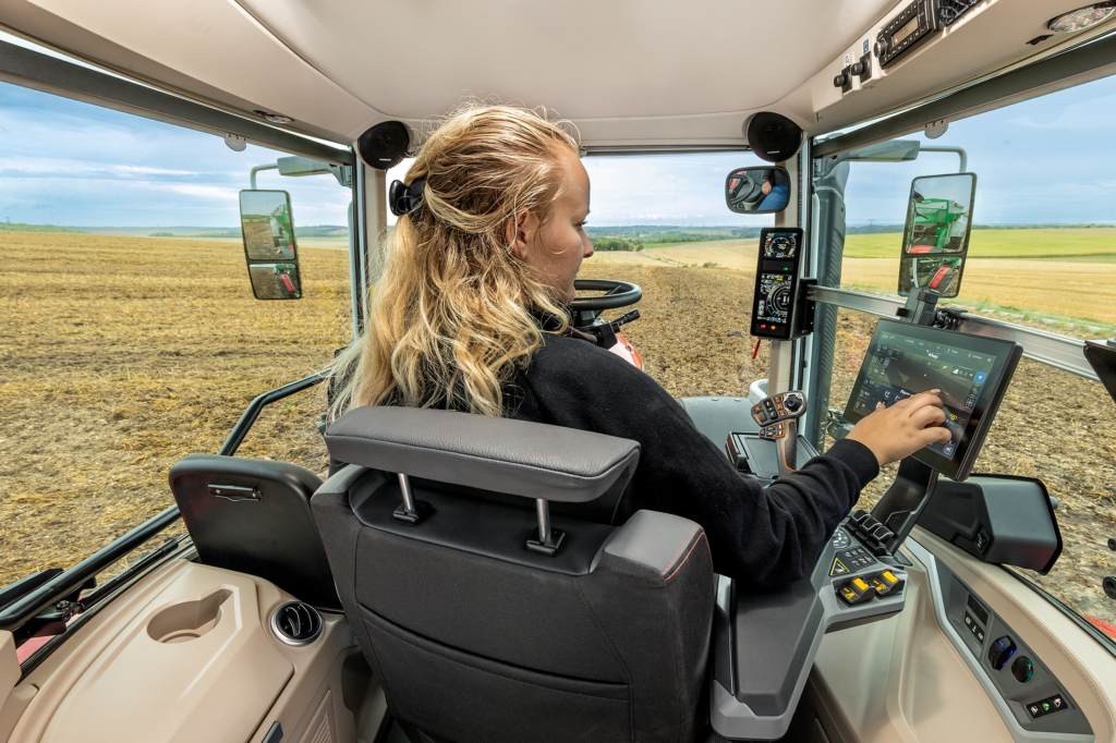 Nainen istumassa Massey Ferguson 7S MARK2 -traktorin ohjaamossa.
