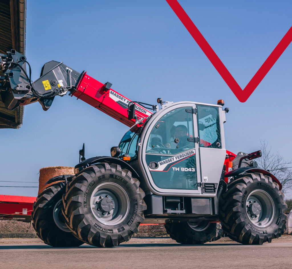 Massey Ferguson -kurottaja nostamassa paaleja maatilalla.