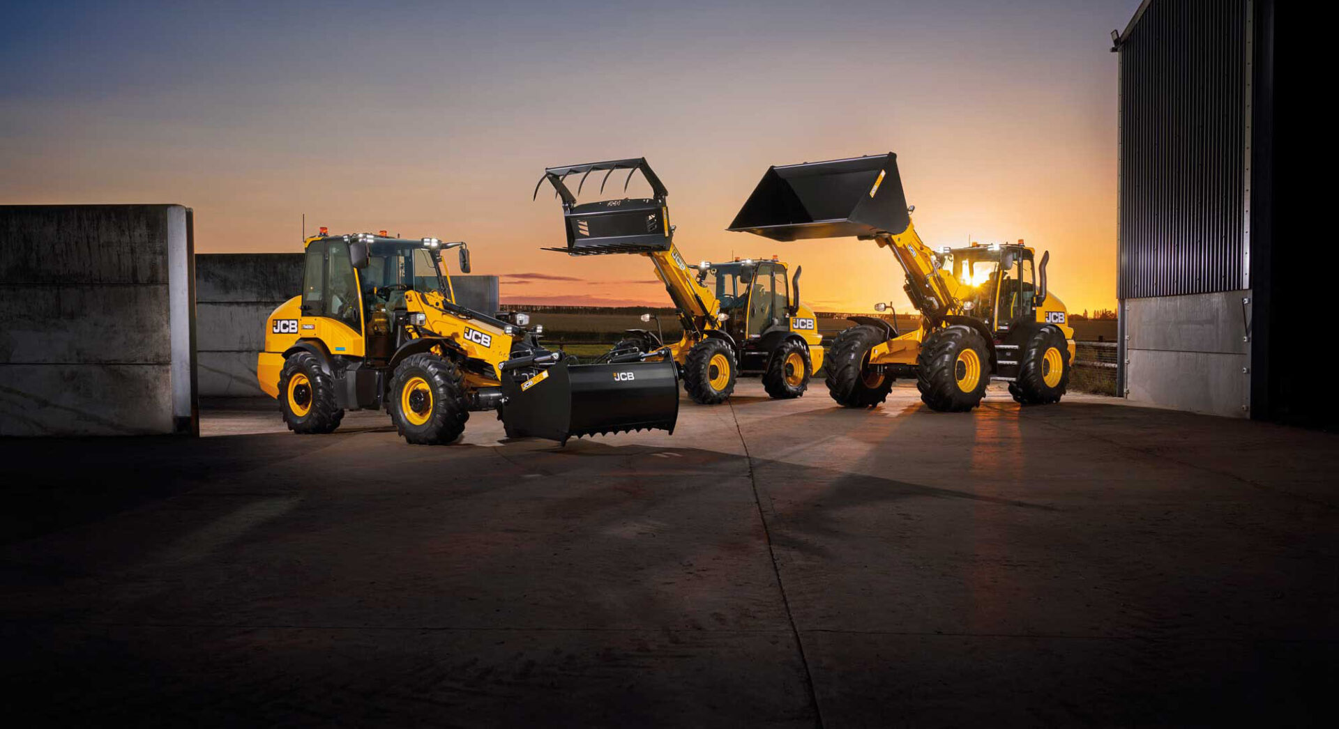 Kolme JCB Telemasteria illan hämärässä.