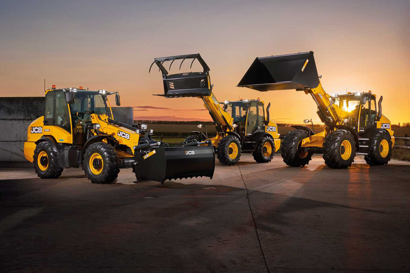 Kolme JCB Telemasteria illan hämärässä.