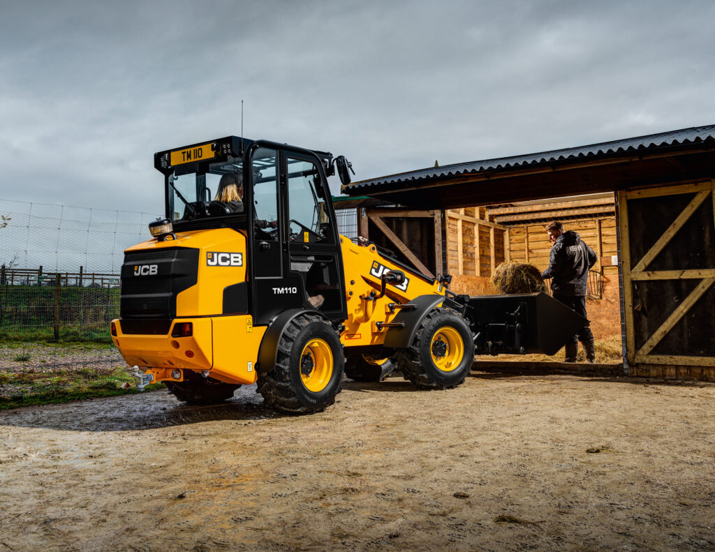 Henkilö lastaamassa olkea JCB TM110 Agri -kurottavaan pyöräkuormaajaan.