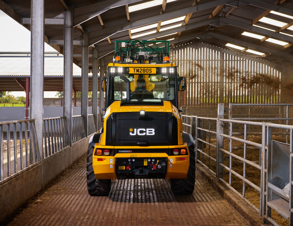 JCB TM280S Agri -kurottava pyöräkuormaaja kuivittamassa navettaa turpeella.