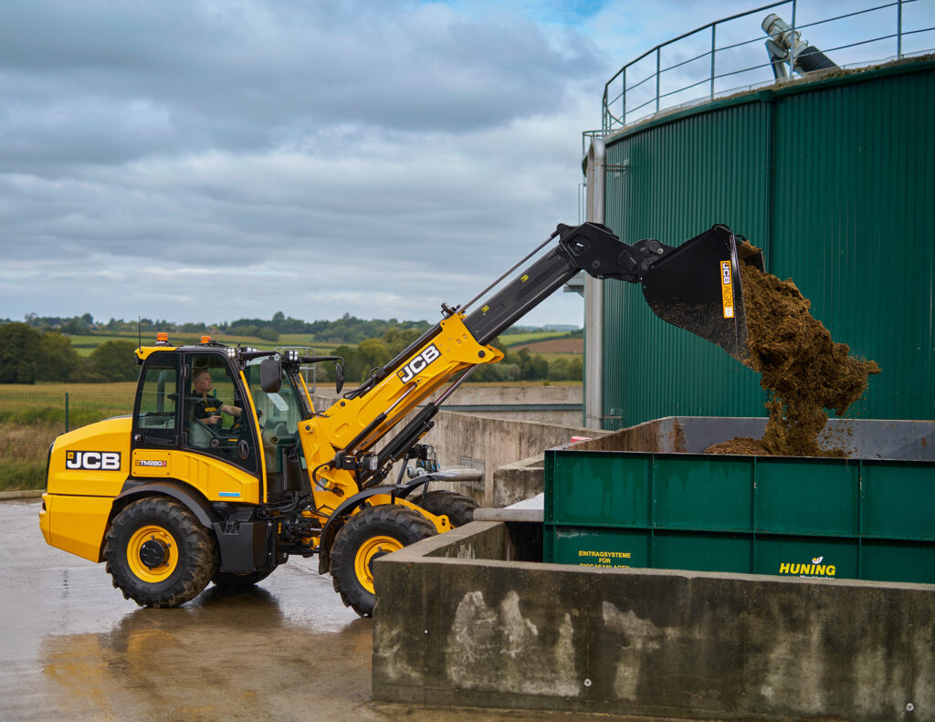 JCB TM280S Agri -kurottava pyöräkuormaaja kaatamassa kuivalantaa kärryyn.